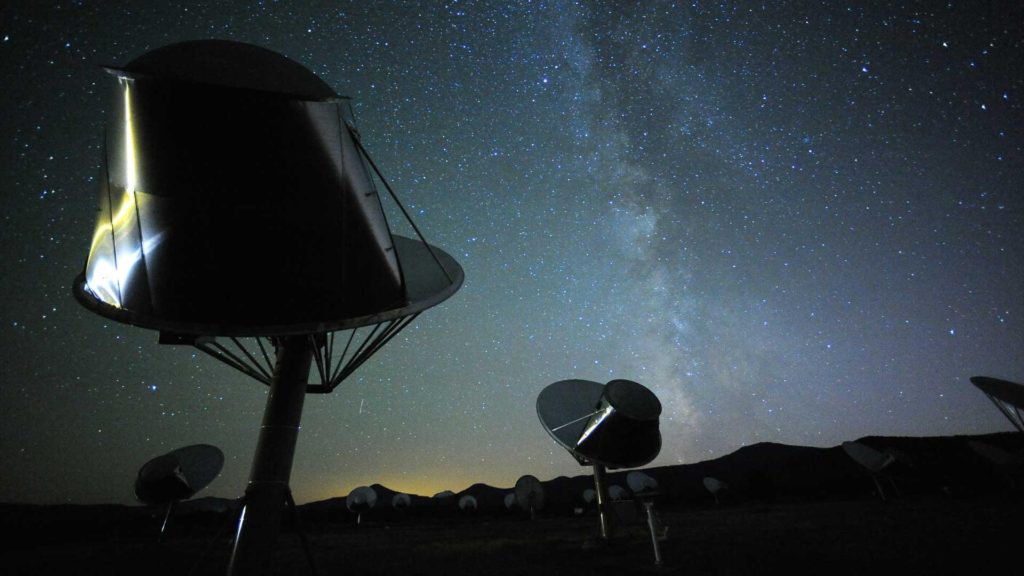 Allen Telescope Array antennae point up at a night sky.