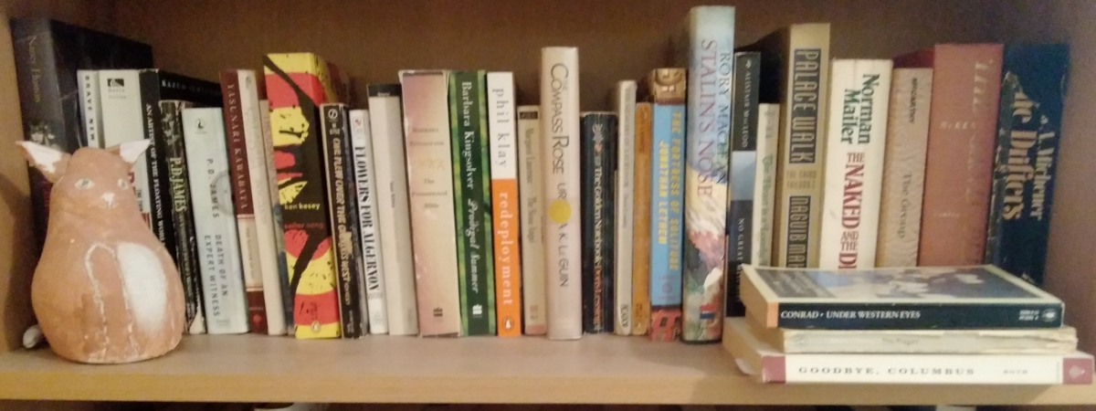 Books and a figurine on a bookshelf.